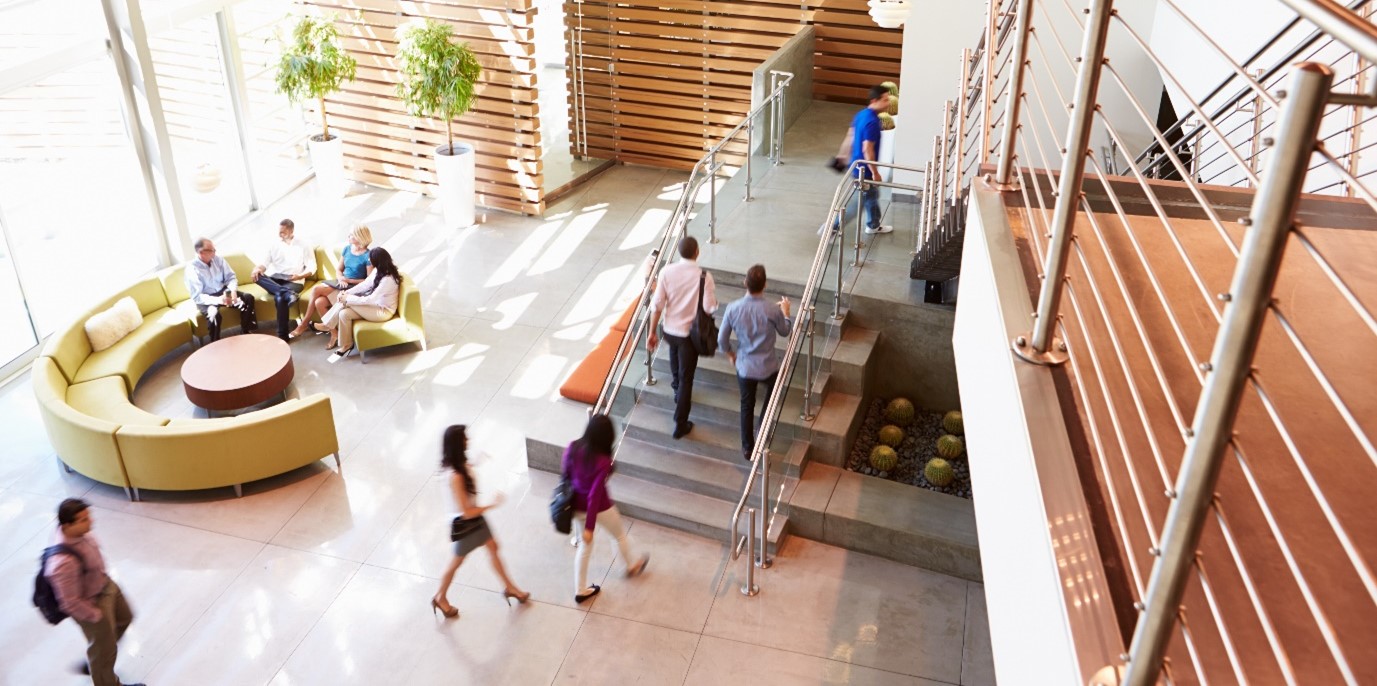 Employees at an international finanical corporation move safely through the reception of a modern office protected by CCTV cameras and an advanced access control system